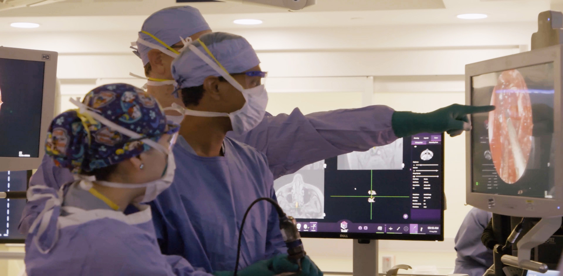 Dr. Yoshor directing residents in surgery by pointing at video on screen